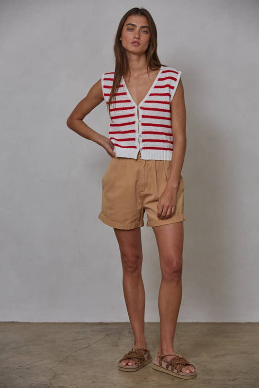 Woman wearing a red and white striped sleeveless top and beige shorts against a plain background