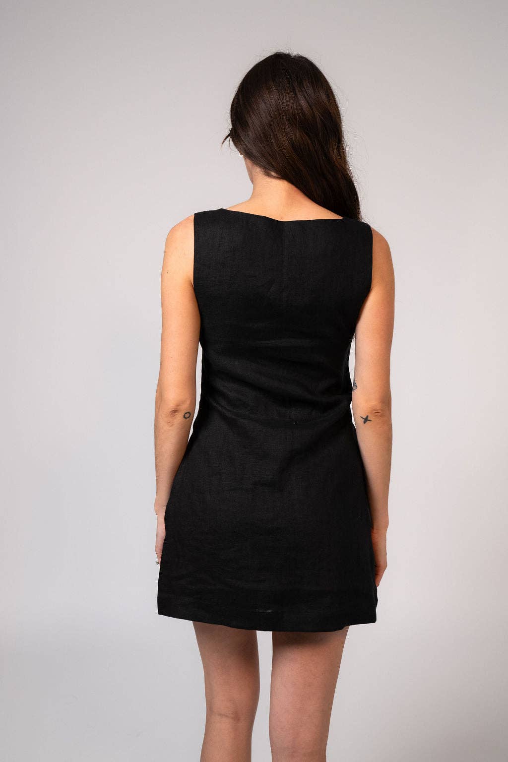 Person wearing a black sleeveless dress against a plain background
