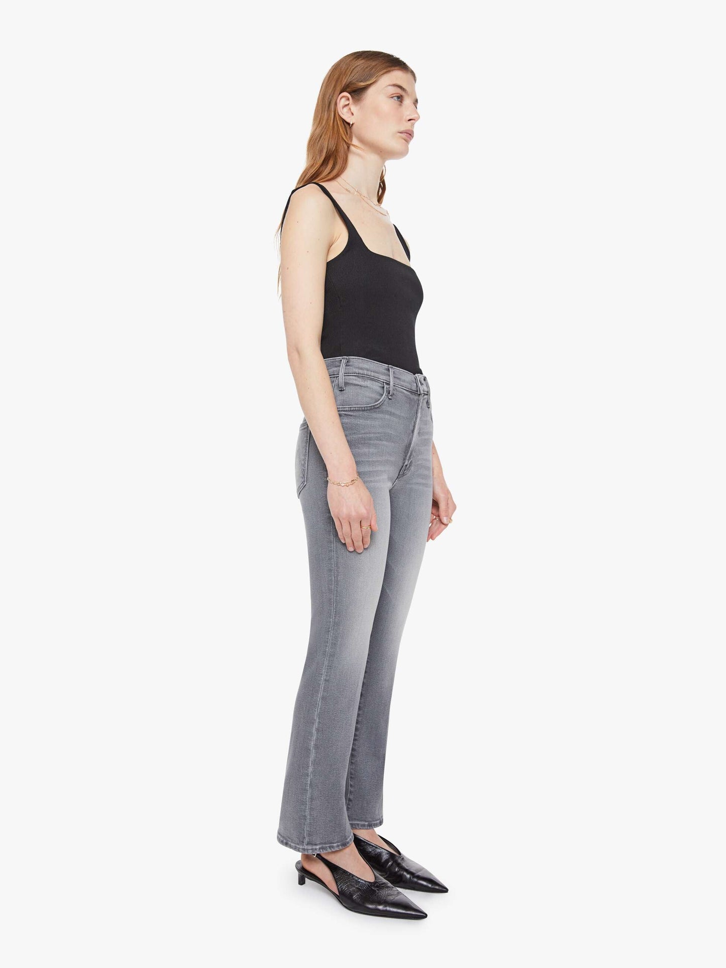 Woman wearing gray jeans and a black top on a white background