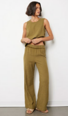 Woman wearing a green sleeveless top and wide-leg pants against a white background