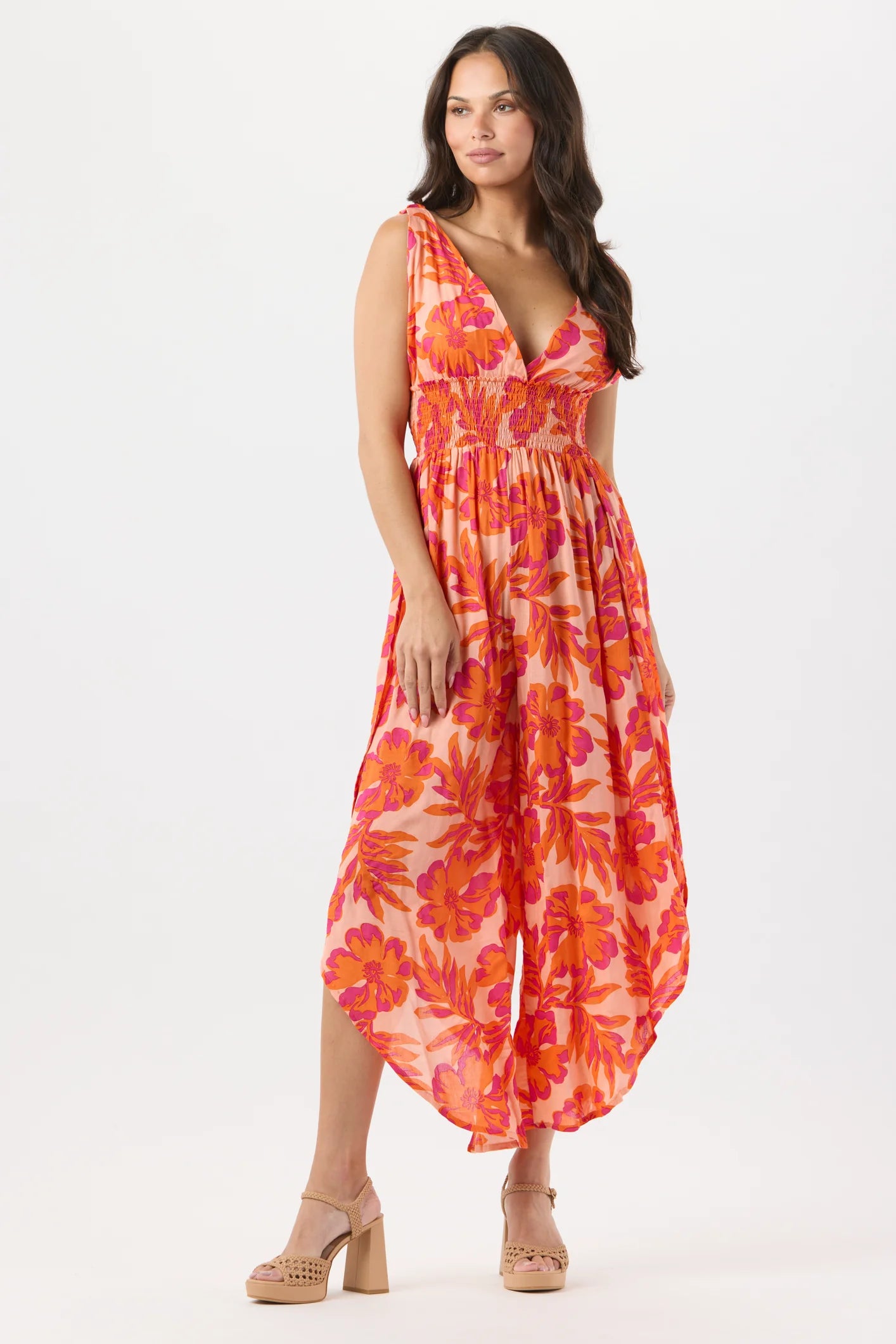 Woman wearing floral jumpsuit in wedge heels on white background.