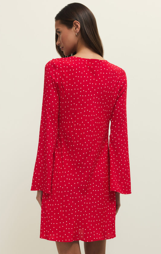 Red polka dot dress worn by a model on a beige background