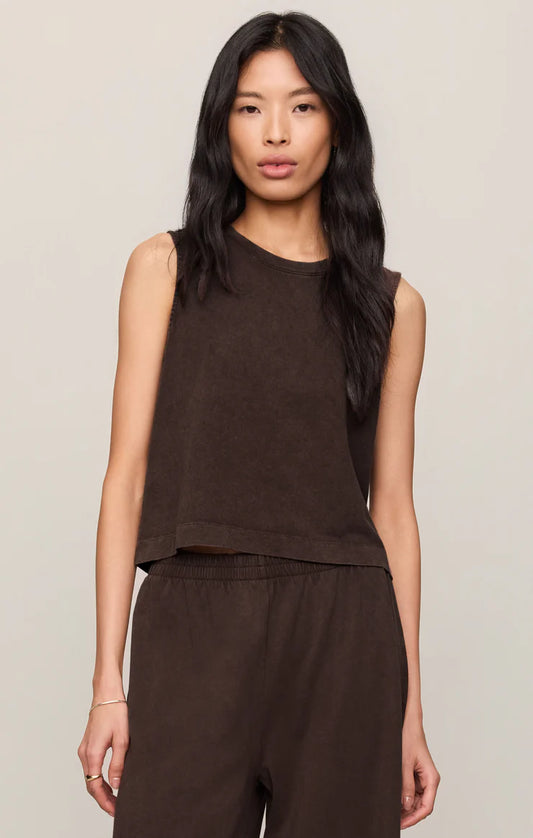 Woman wearing a brown sleeveless top and pants against a plain background