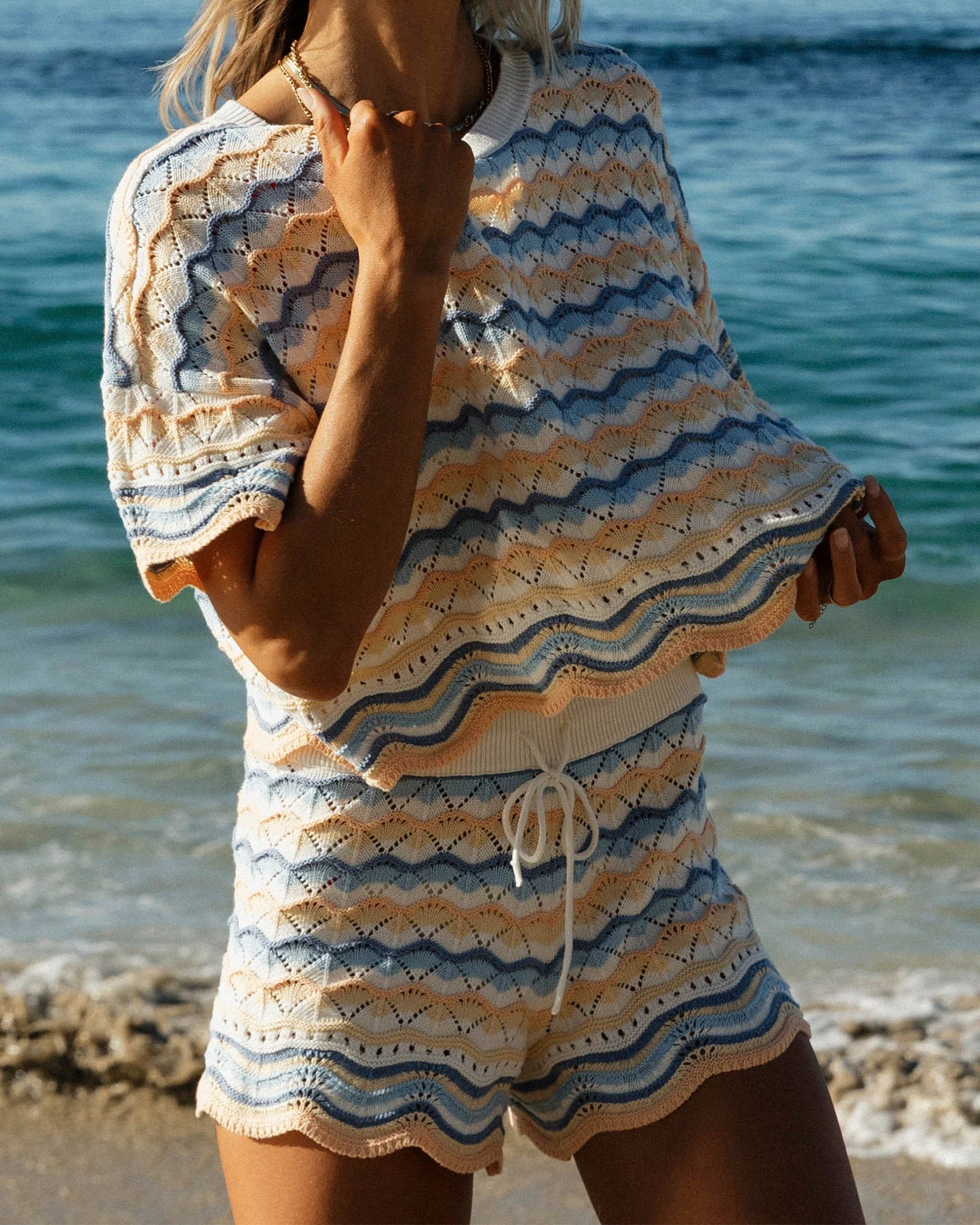Person wearing a patterned cover-up on a beach with ocean in the background