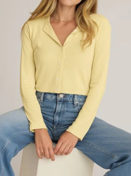 Person wearing a yellow long-sleeve shirt and blue jeans on a plain background