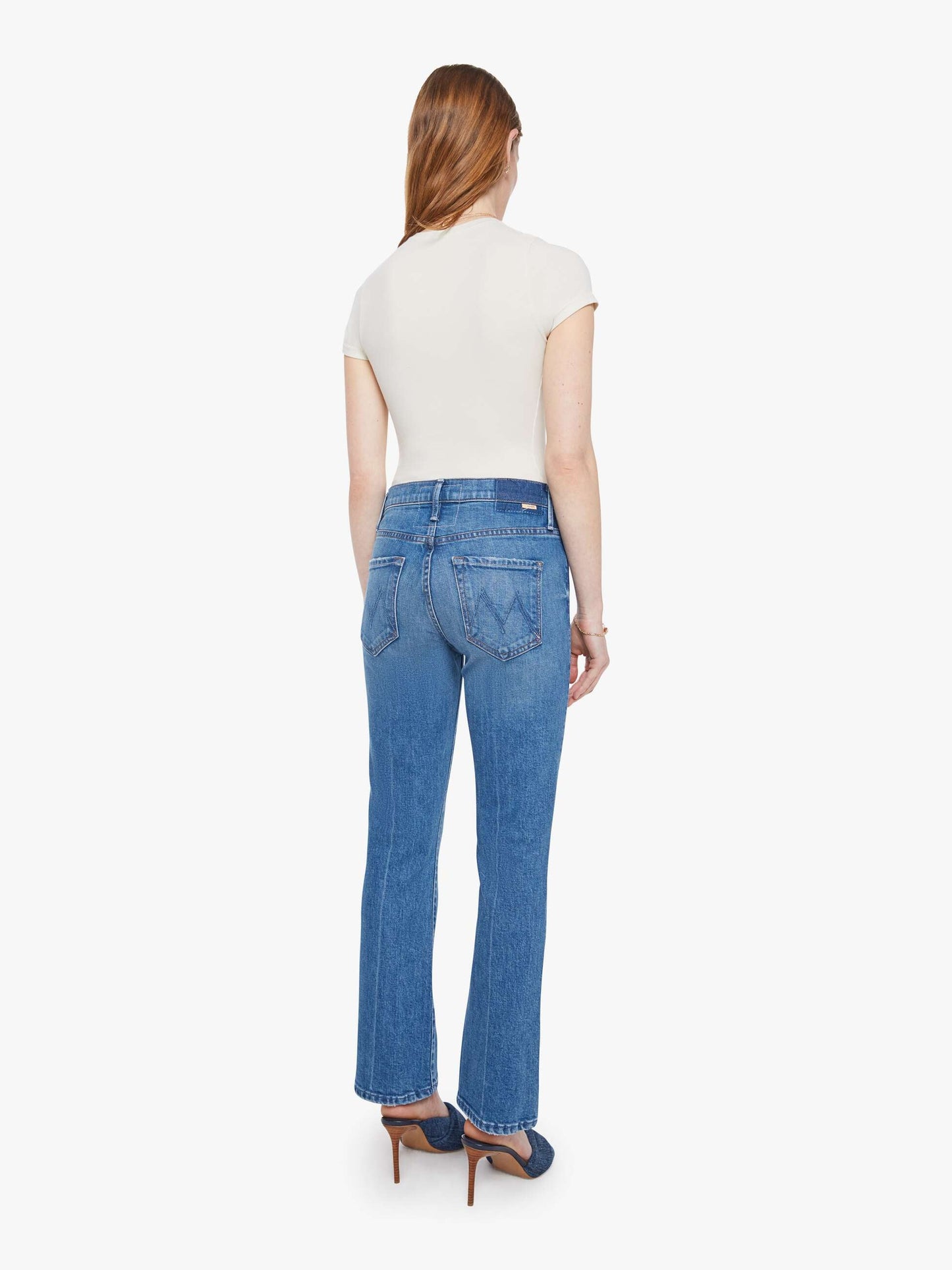 Woman wearing blue jeans and a white top on a white background