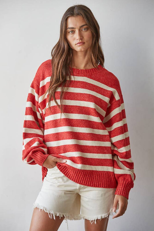 Woman wearing a red and white striped sweater with white shorts on a plain background