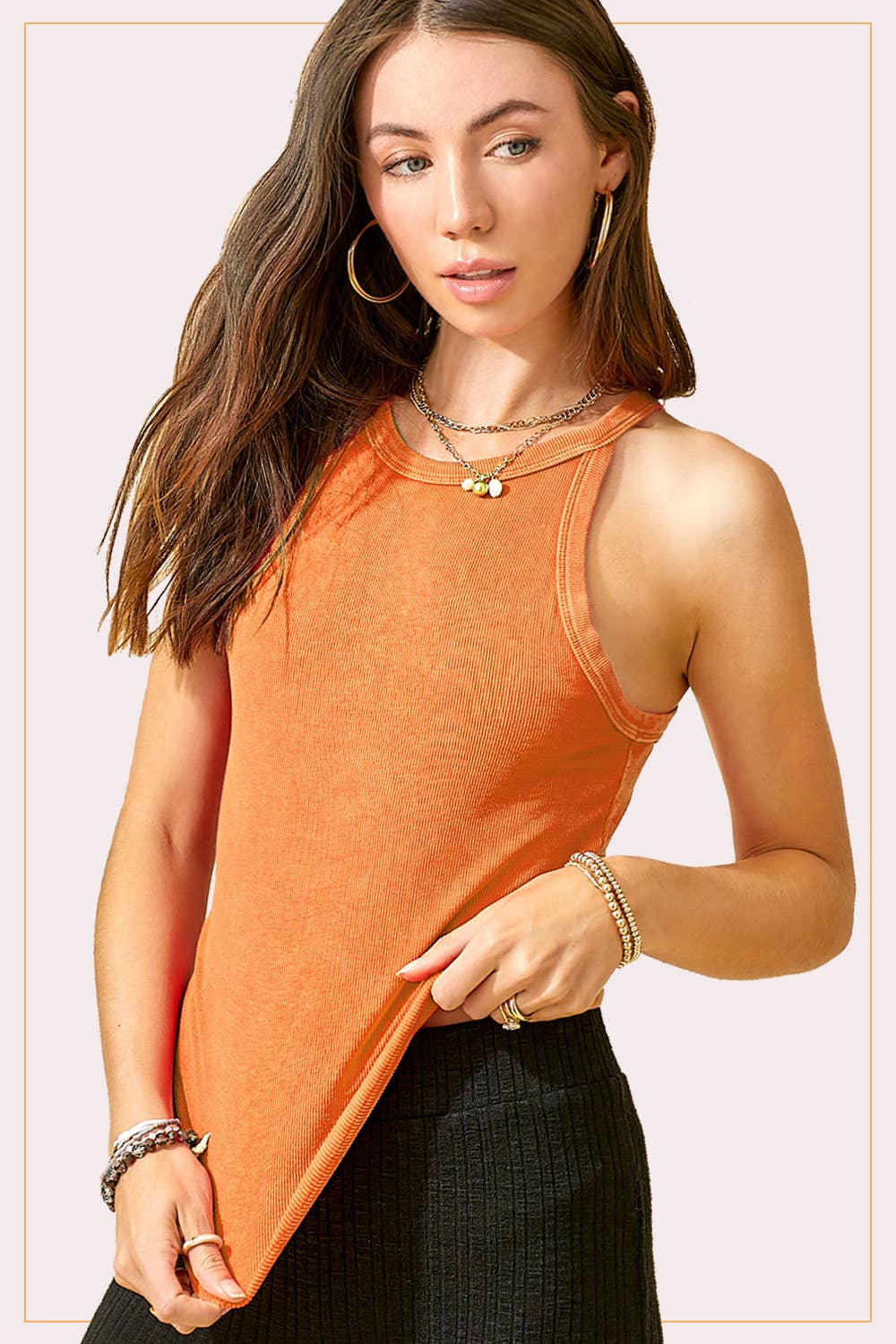Woman wearing an orange sleeveless top with a plain background