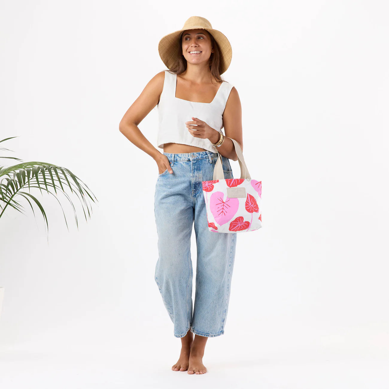 Woman holding a tote bag with pink floral design on a white background