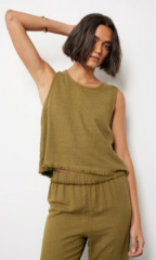 Woman wearing a green sleeveless top and pants against a white background