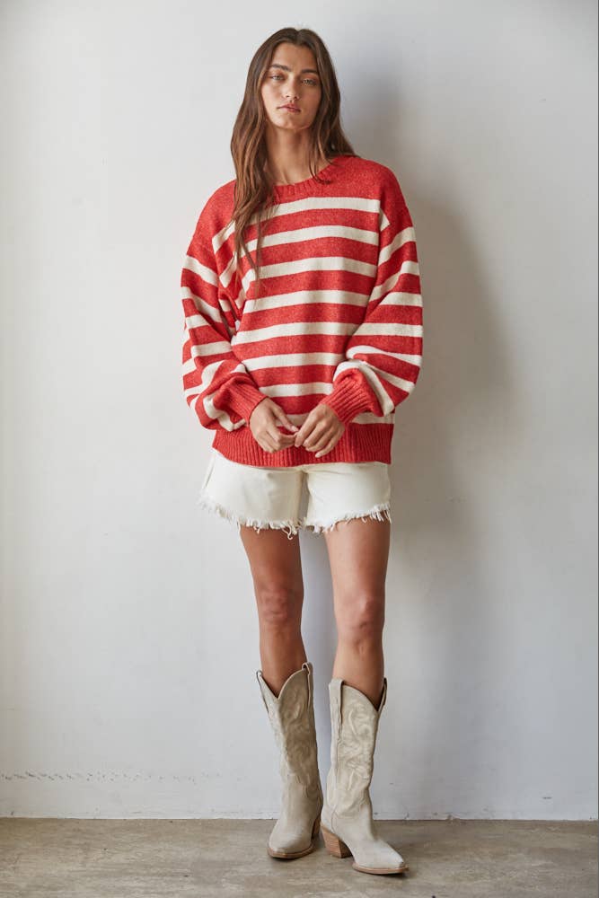 Person wearing a red and white striped sweater with white shorts and beige boots against a plain background