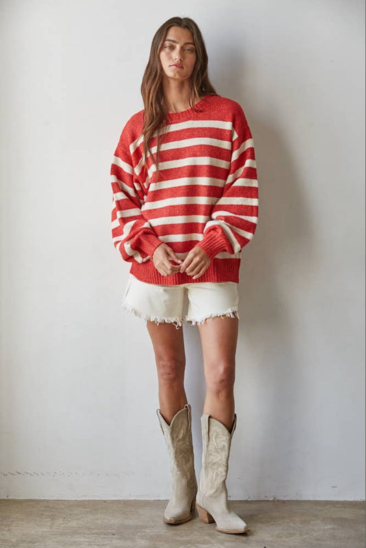 Person wearing a red and white striped sweater with white shorts and beige boots against a plain background