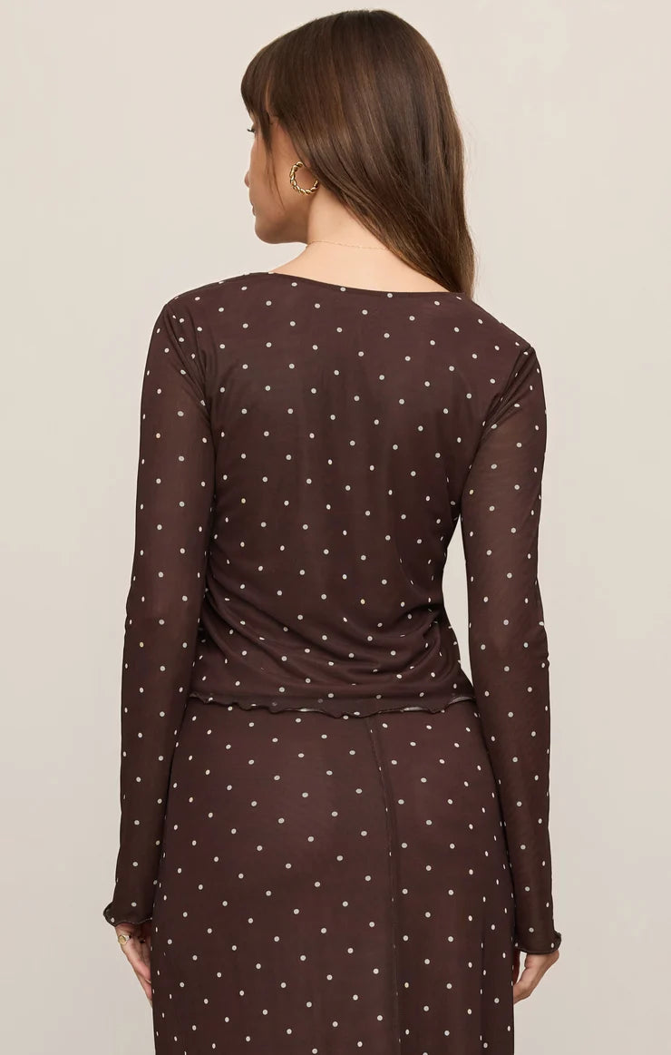 Woman wearing a brown polka dot dress against a beige background