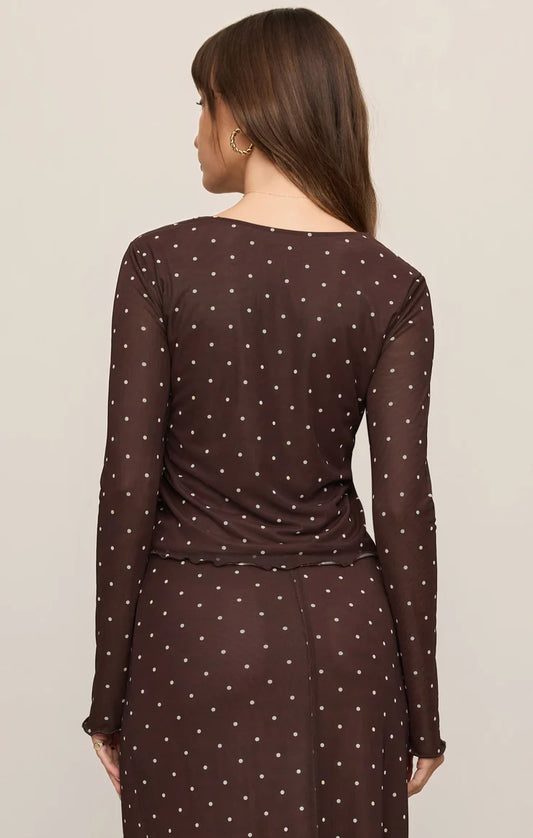 Woman wearing a brown polka dot dress against a beige background
