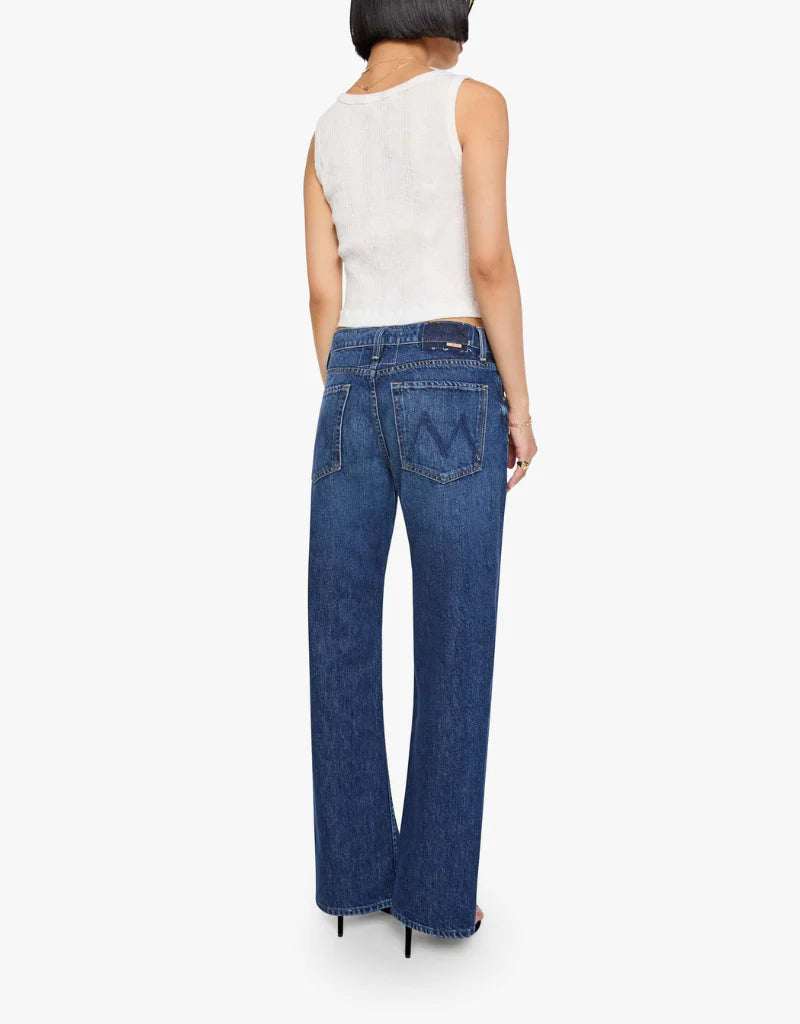 A woman shown from the back wearing blue wide-leg jeans and a white sleeveless top against a light gray studio background.
