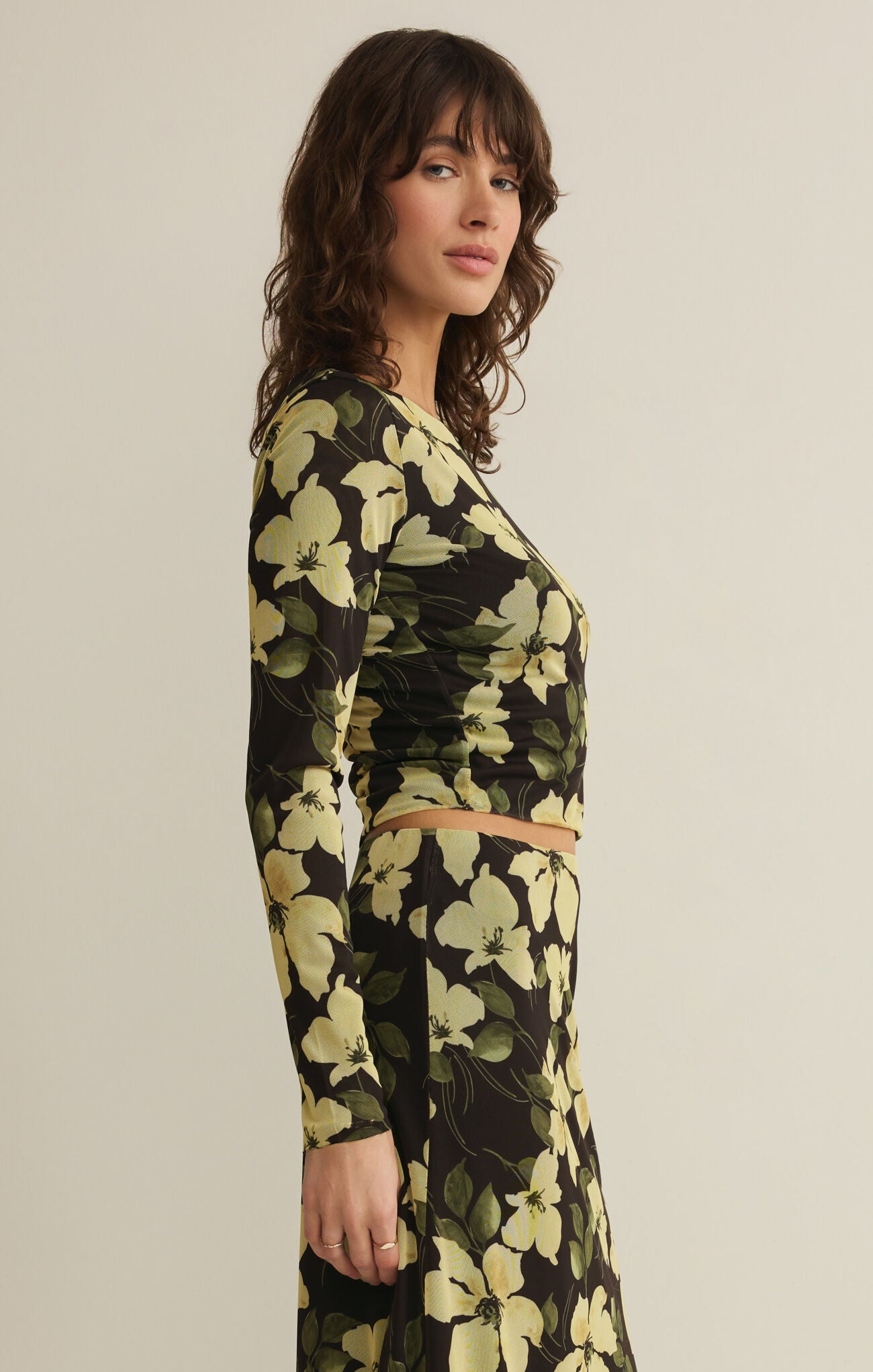 Woman wearing a green floral skirt against a beige background