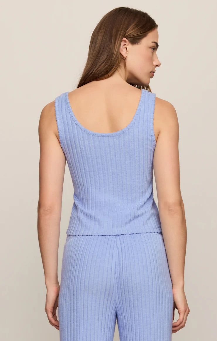 A woman shown from the back wearing a light blue ribbed knit sleeveless top and matching pants against a plain light beige studio background.