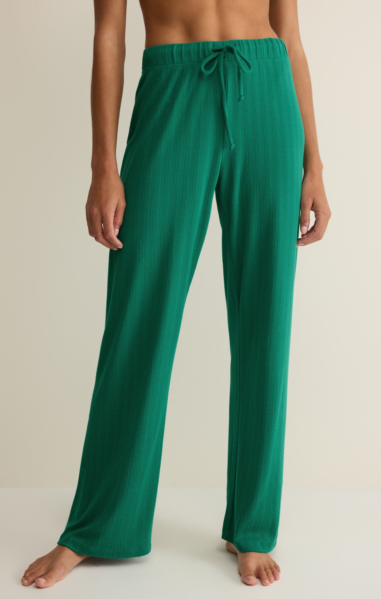 Woman wearing green pants against a white background.