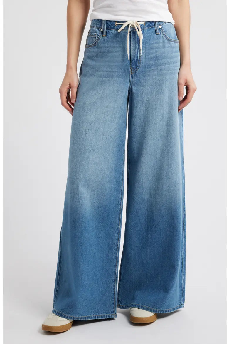 Person wearing blue wide-leg jeans on a white background