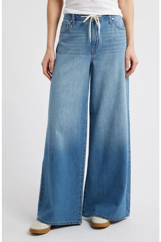 Person wearing blue wide-leg jeans on a white background