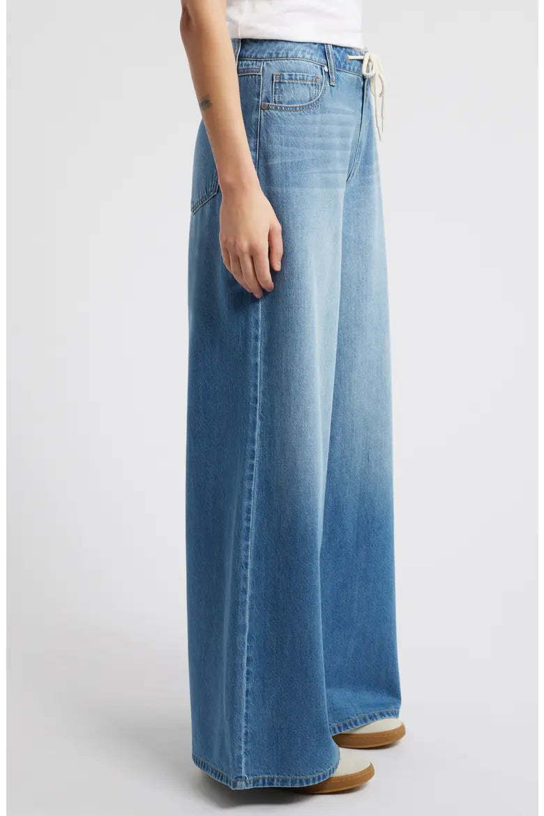 Long blue denim skirt worn by a person on a white background