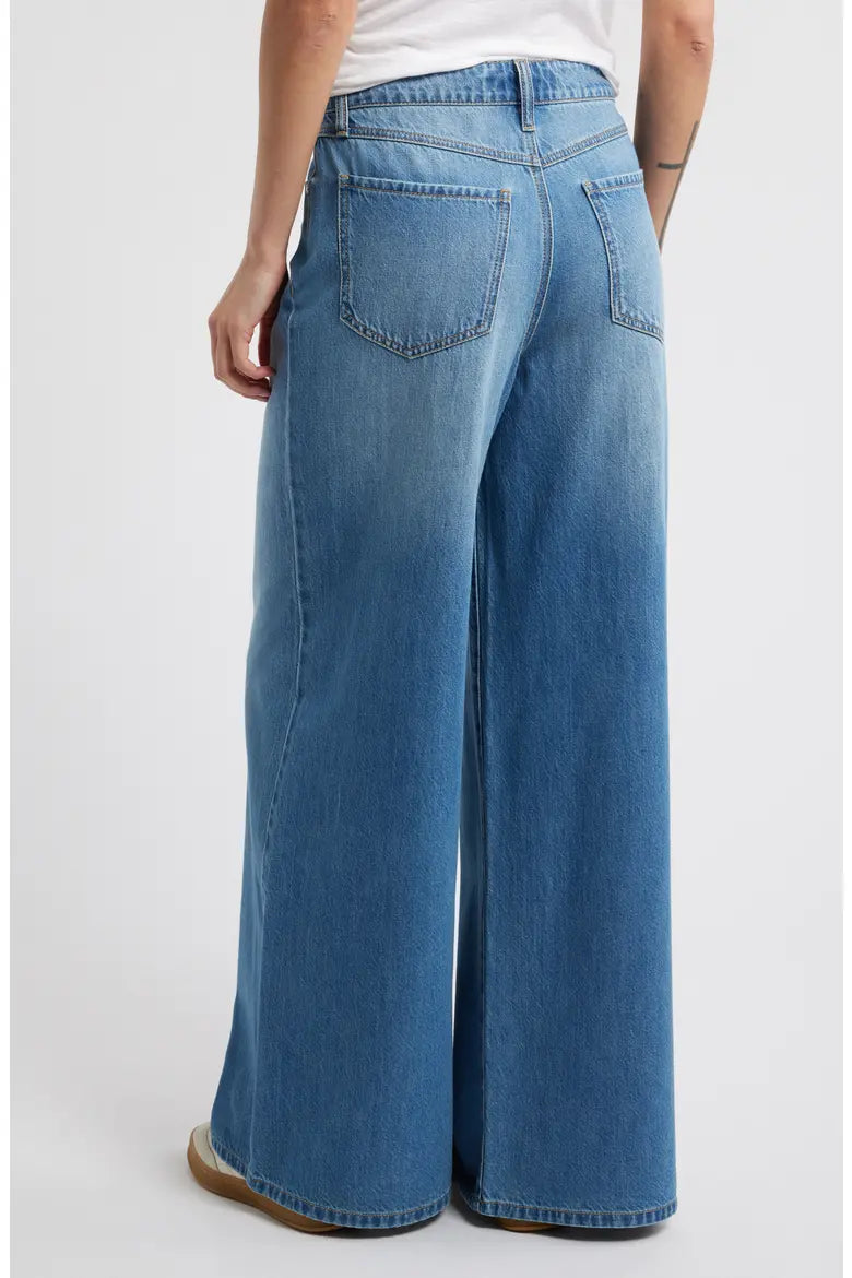 Blue wide-leg jeans worn by a person on a white background