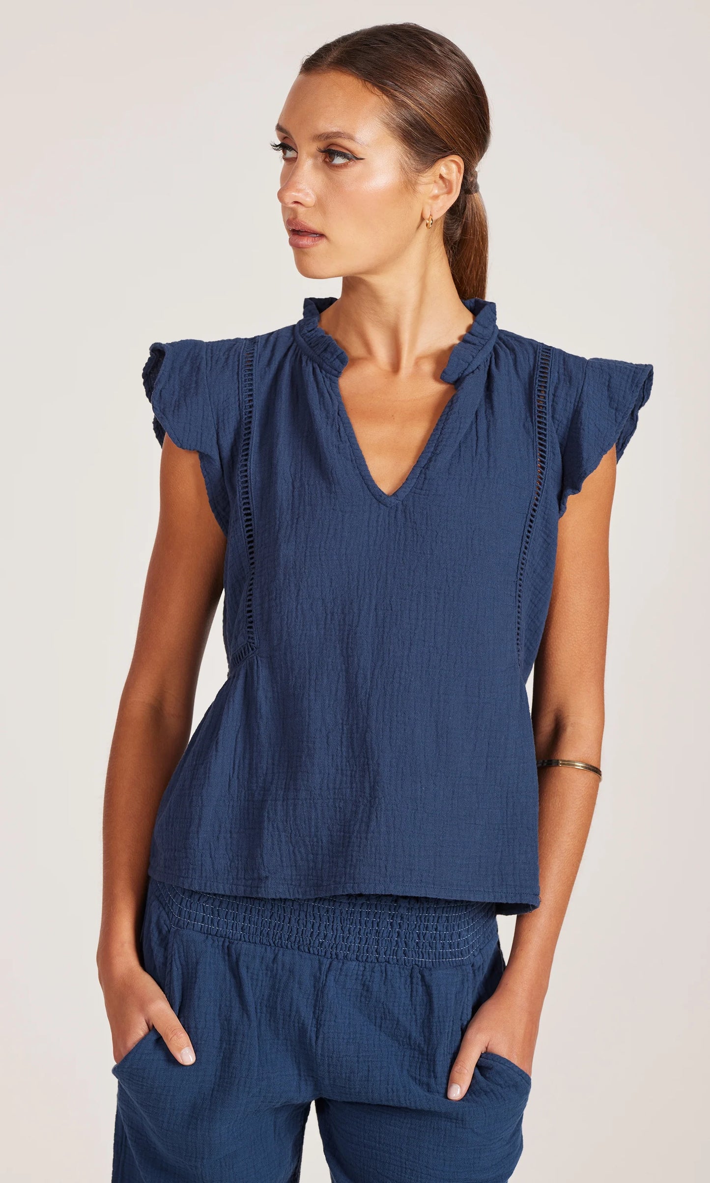 Woman wearing a blue top and pants on a white background