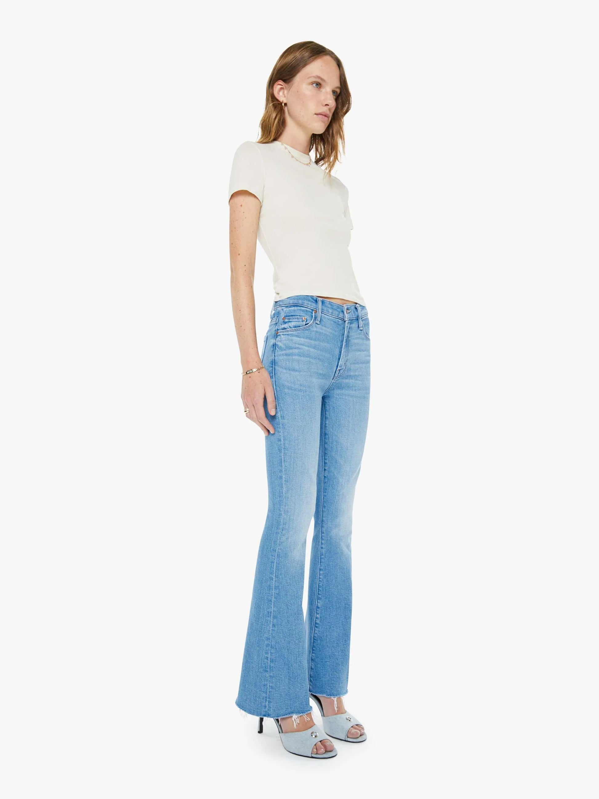 Woman wearing a white top and light blue jeans on a white background