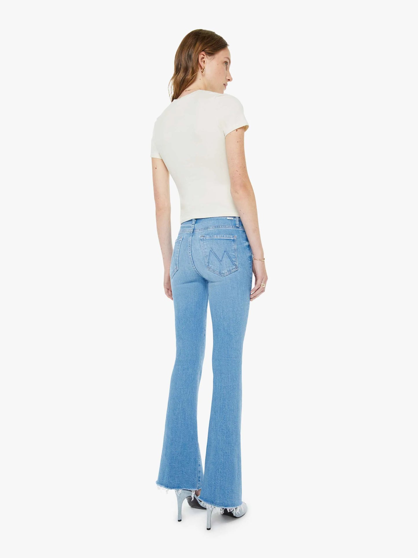 Woman wearing a white top and light blue flared jeans on a white background