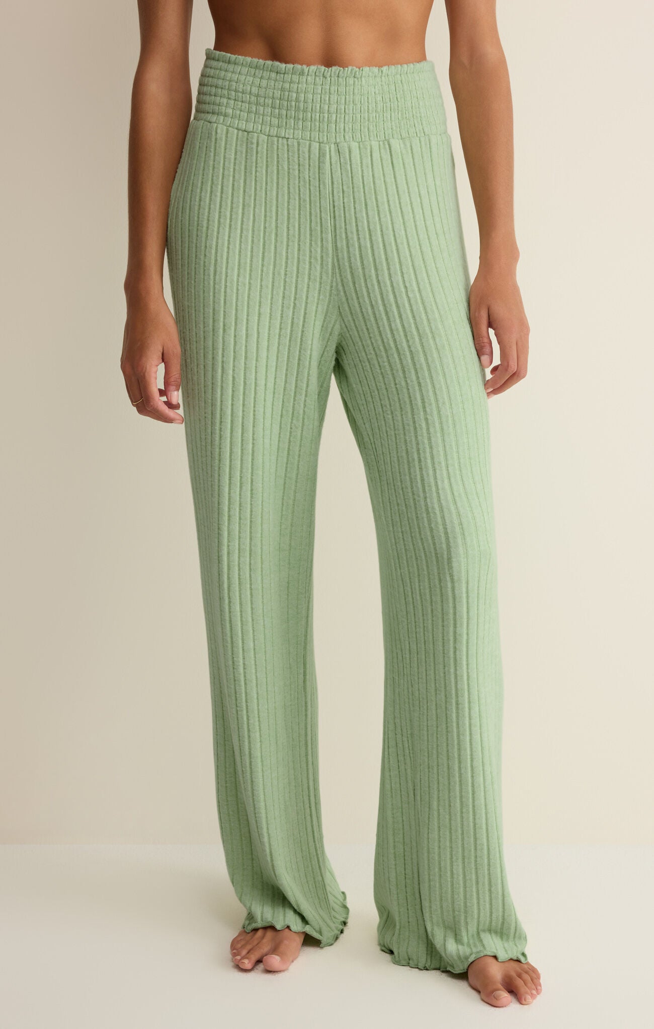Green ribbed pants worn by a person on a neutral background