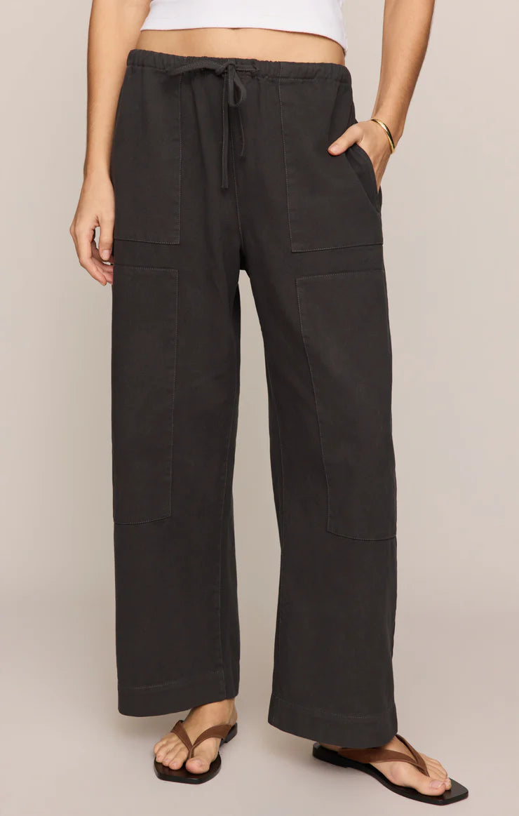 Person wearing black wide-leg pants with a beige background