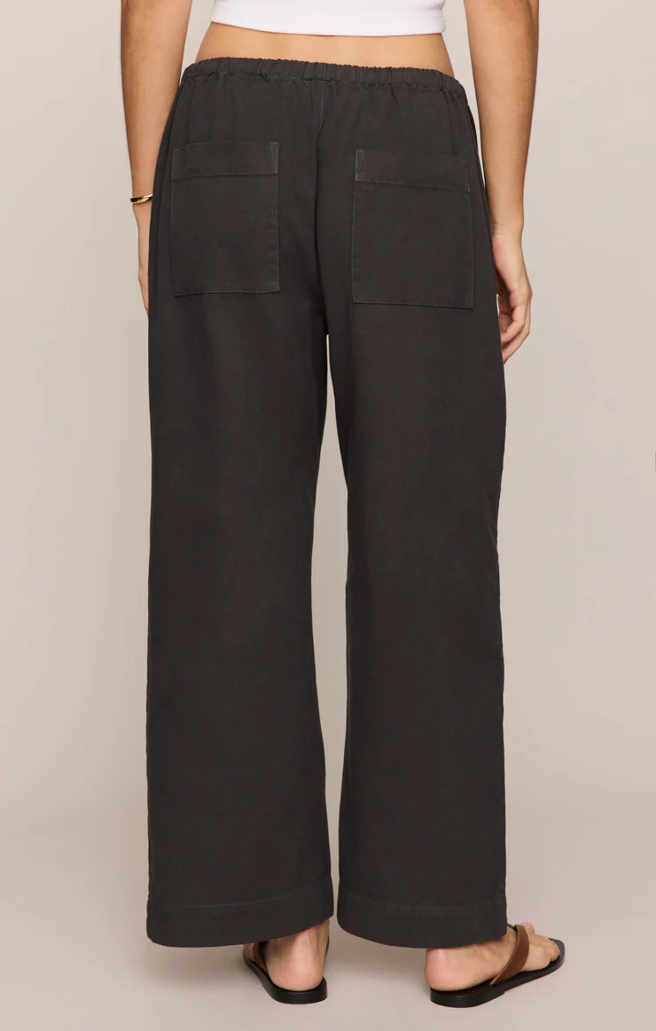 Black wide-leg pants worn by a person on a beige background