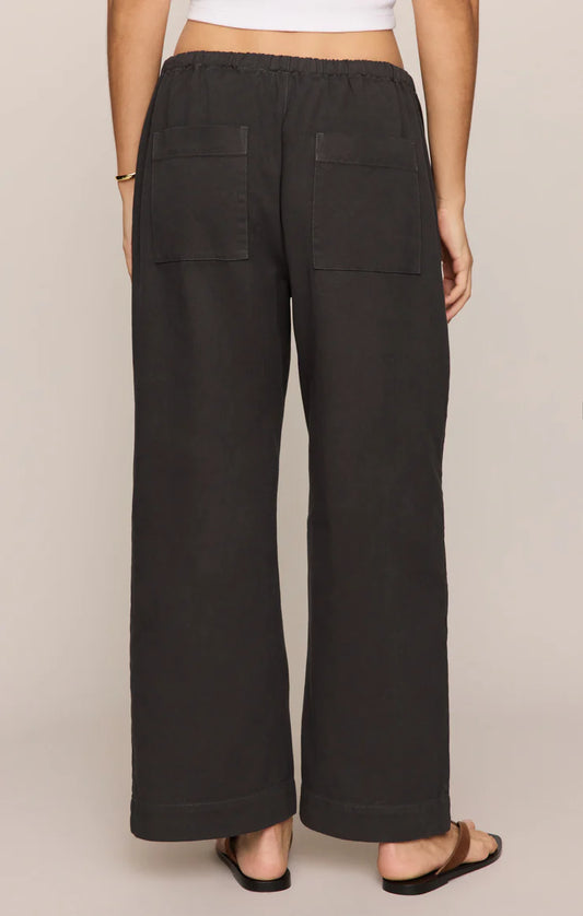 Black wide-leg pants worn by a person on a beige background