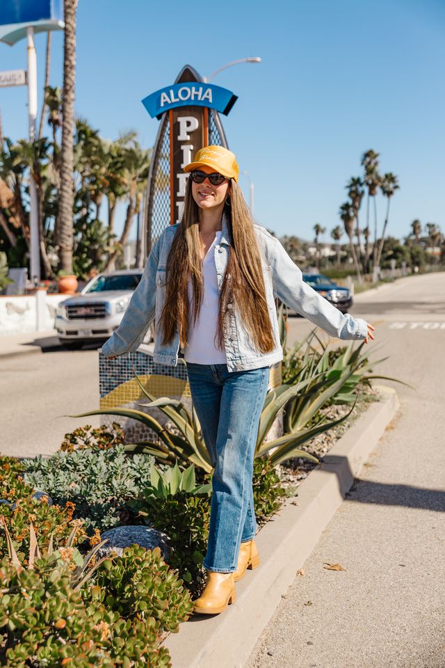Woman standing on a street corner with palm trees and a 'Pineapple' sign in the background.