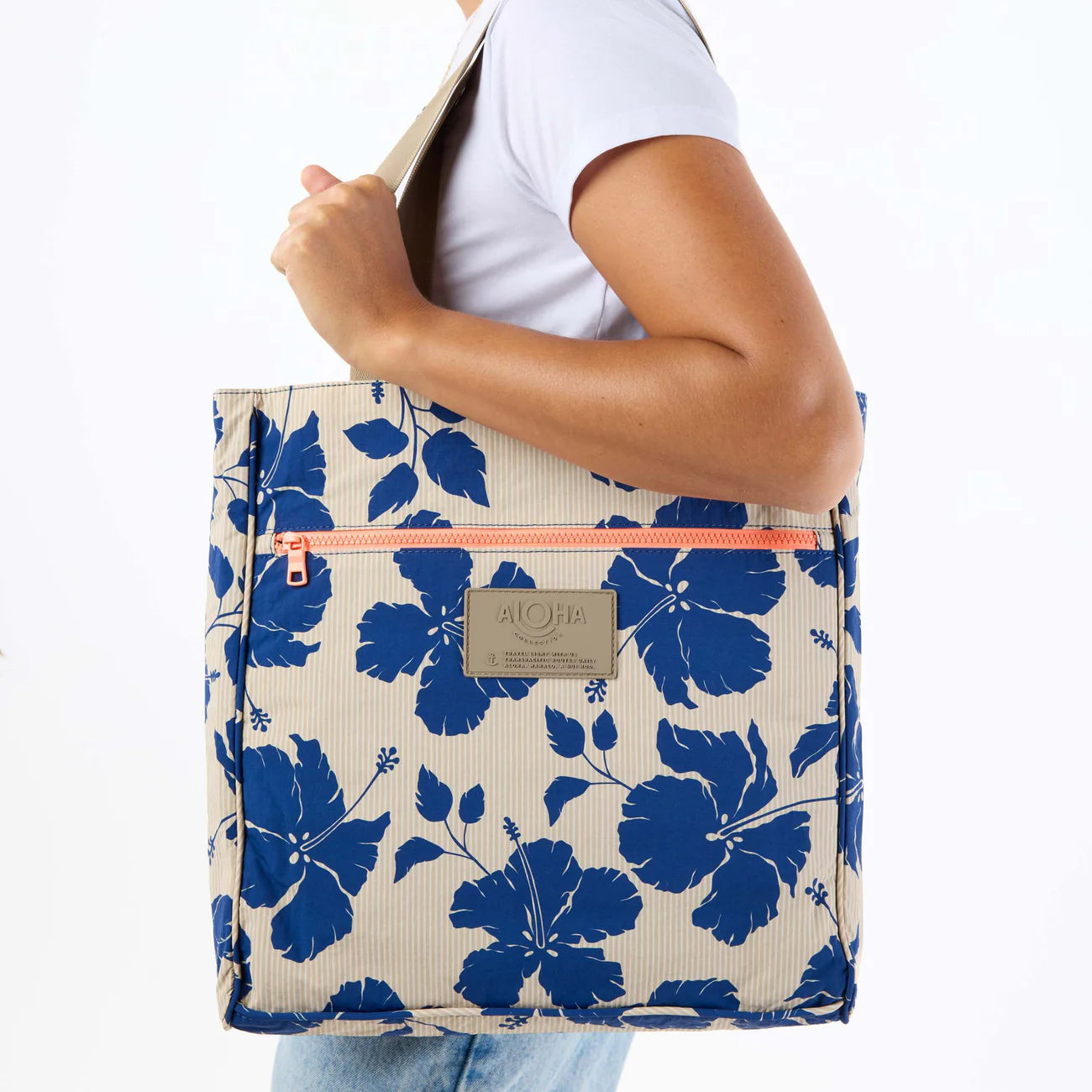 Person holding a tote bag with blue floral pattern on a white background