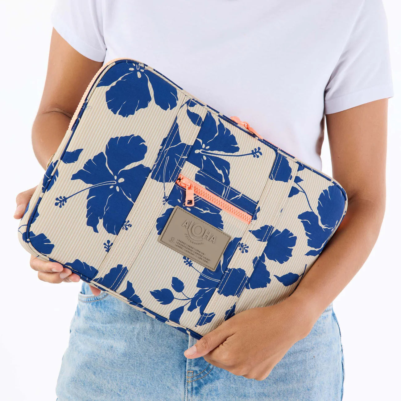Person holding a floral-patterned clutch bag with a visible brand logo.