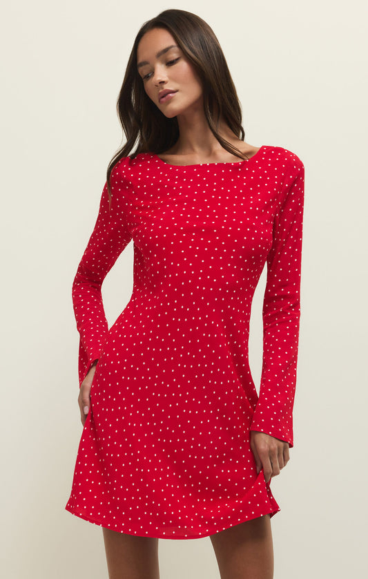 Woman wearing a red polka dot dress against a beige background