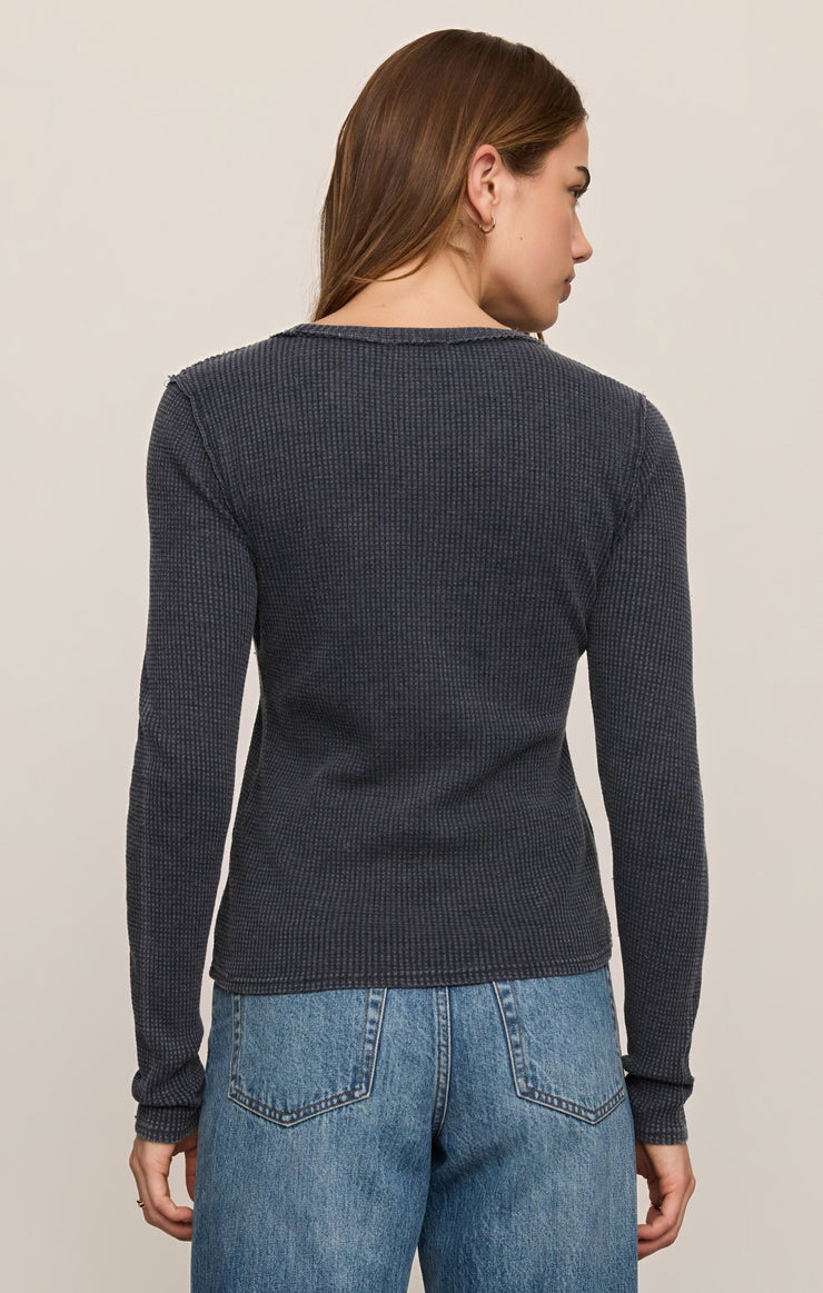 Woman in dark blue longsleeve and blue jeans on white background.