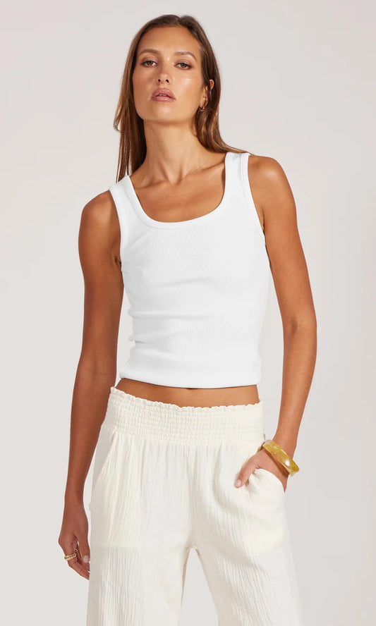Woman in white tank and white pants on white background.