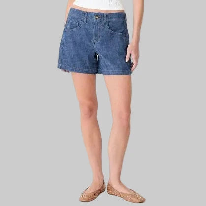 Person in blue shorts and tan flats on grey background.