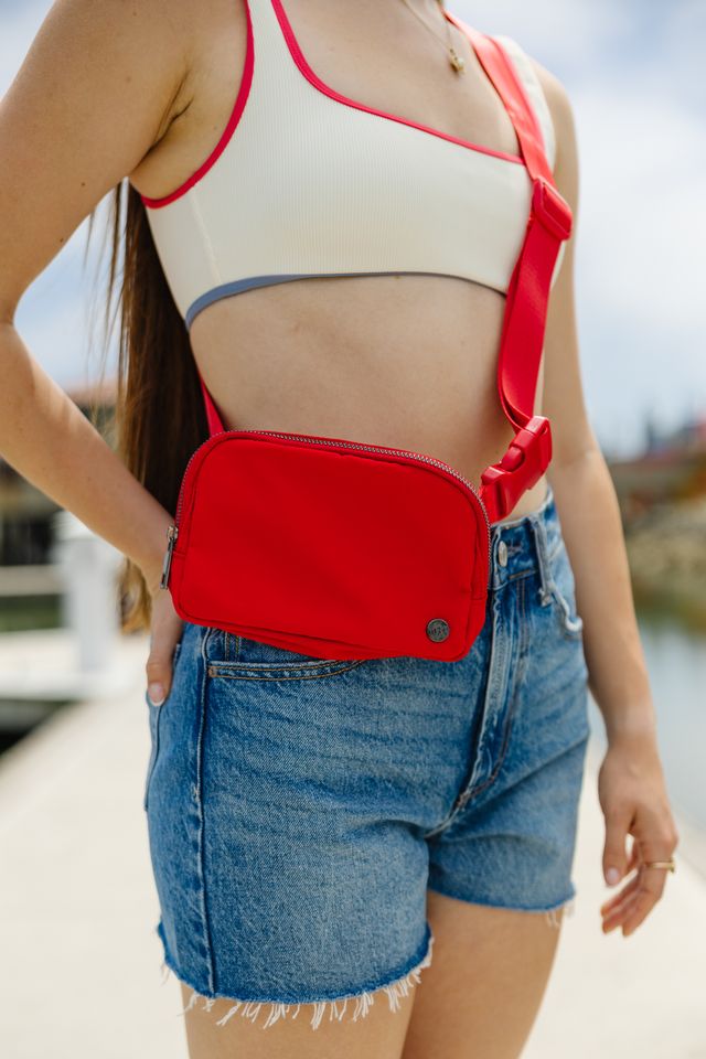 Person wearing a red crossbody bag with a blurred background