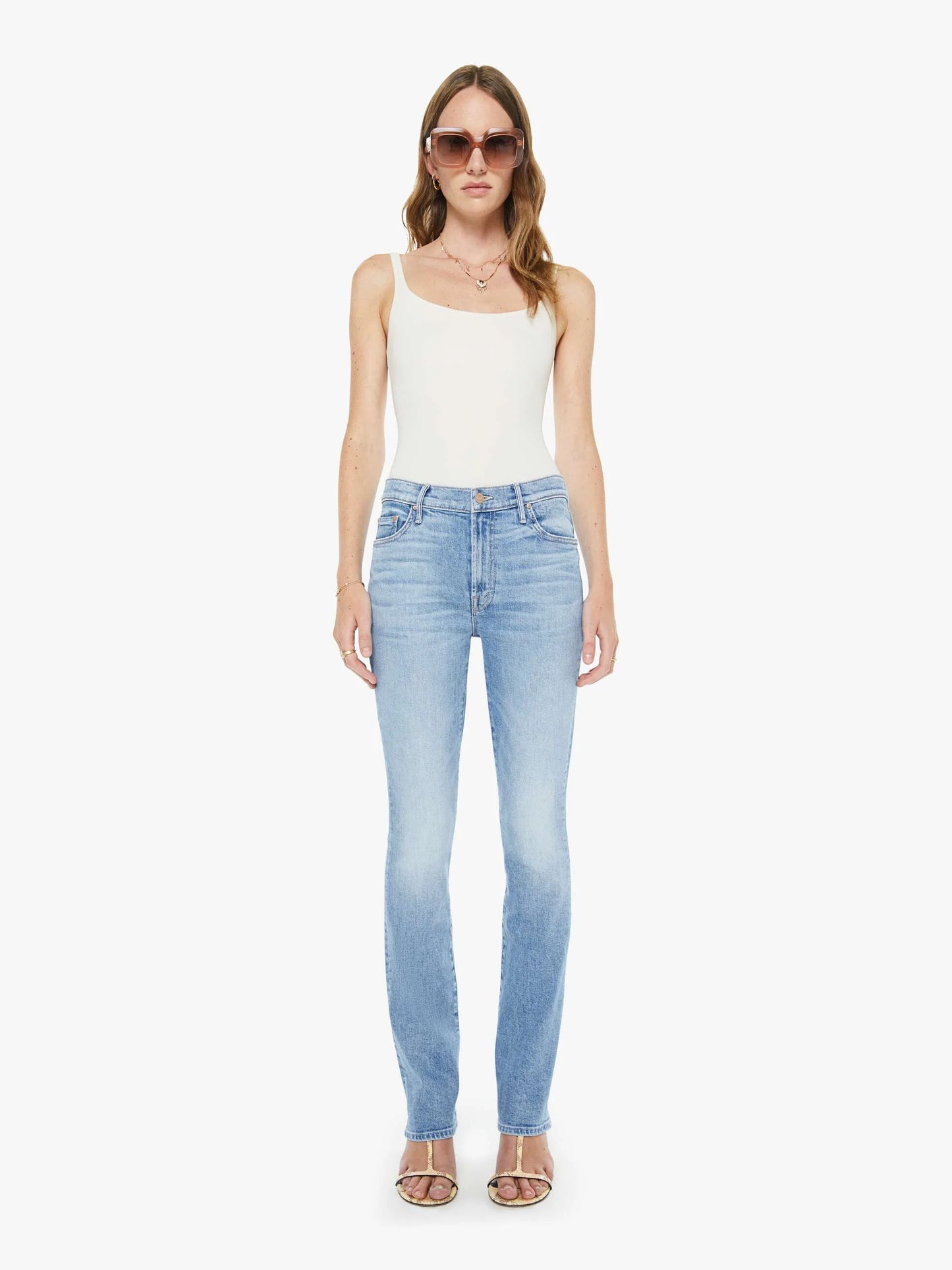 Woman wearing light blue jeans and a white top on a white background