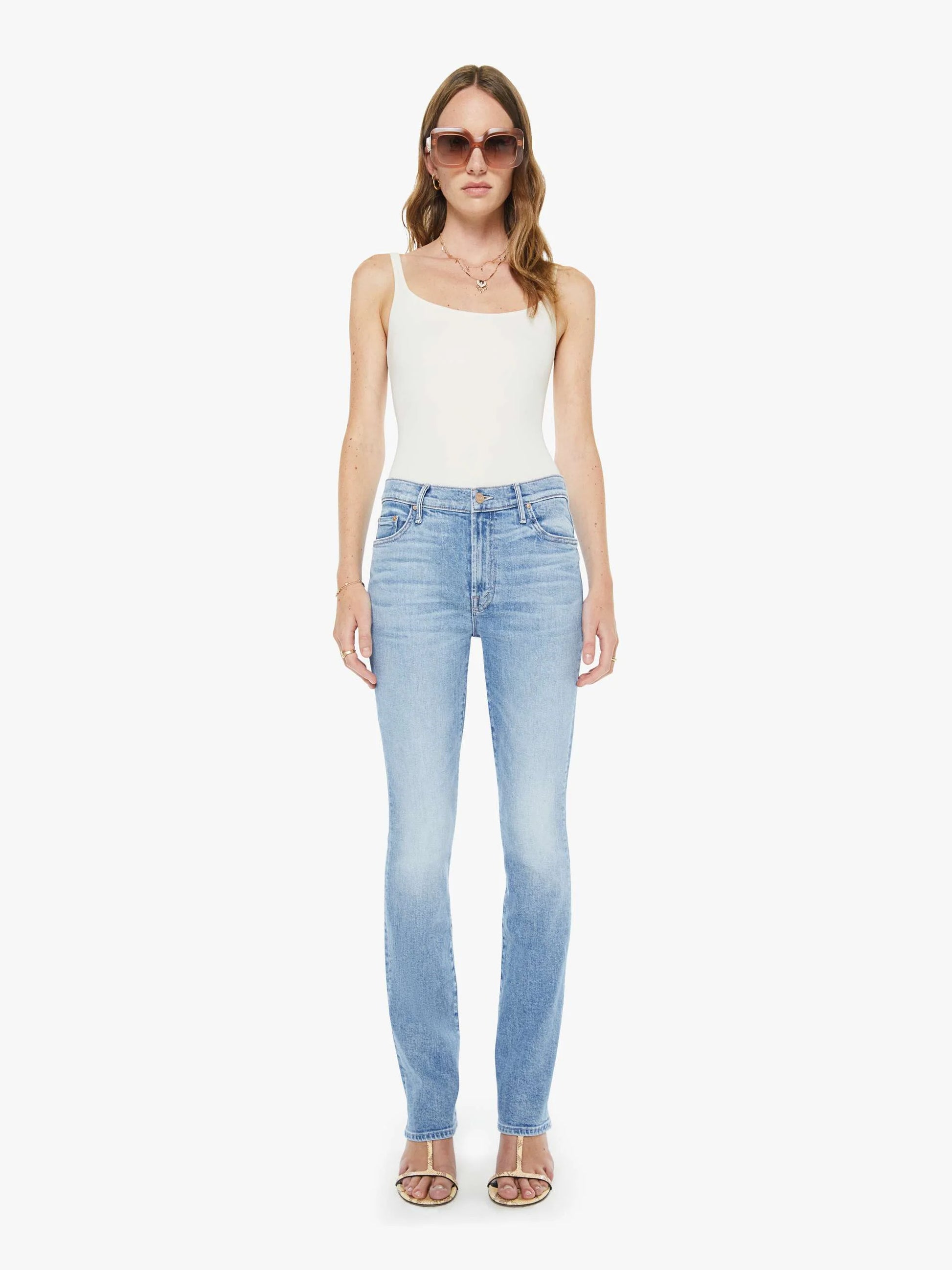 Woman wearing light blue jeans and a white top on a white background