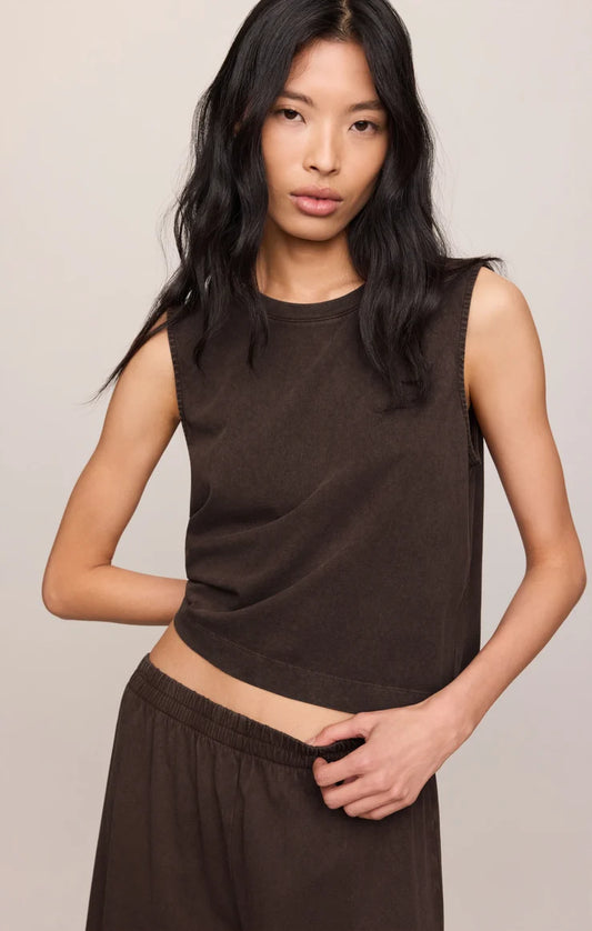 Woman wearing a brown sleeveless top and skirt against a plain background