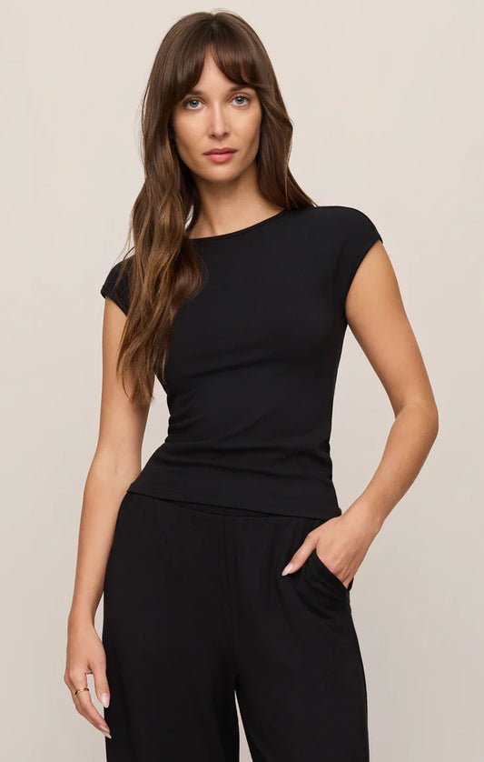 Woman wearing a black top and black pants against a beige background