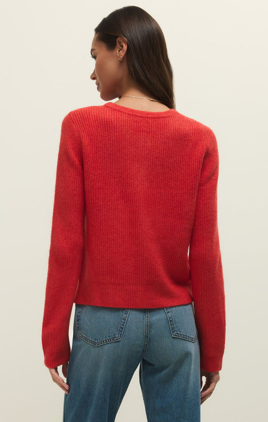 Person wearing a red sweater and blue jeans on a beige background