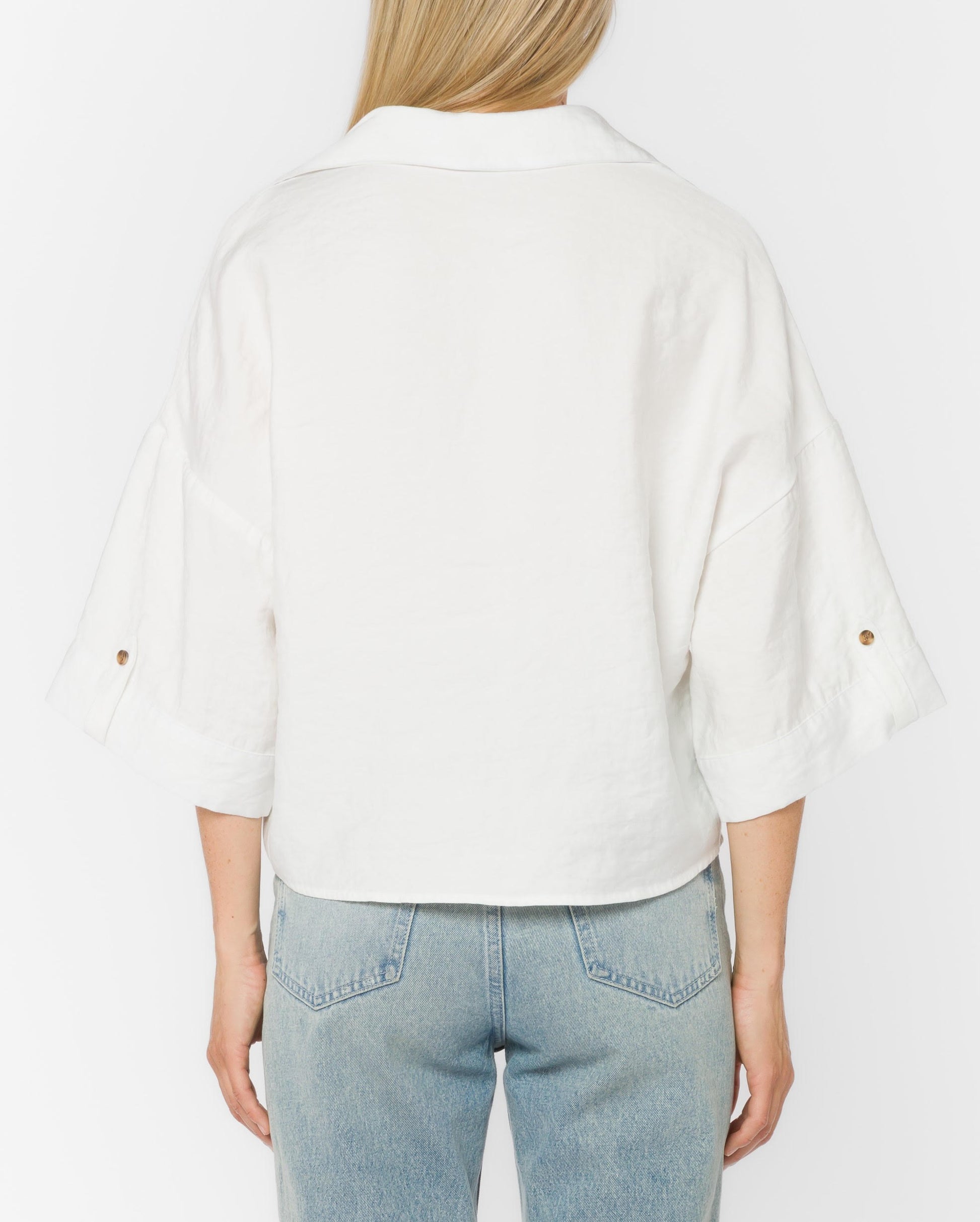 Person wearing a white shirt and light blue jeans on a plain background