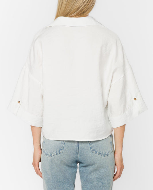 Person wearing a white shirt and light blue jeans on a plain background